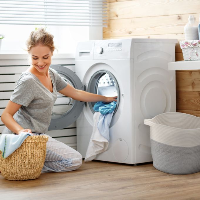 یک خانم در حال استفاده از ماشین لباسشویی است
