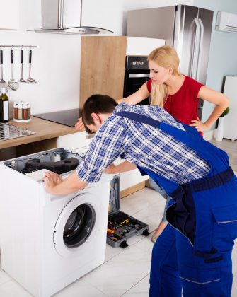 تعمیرکار لباسشویی در حال تعمیر برد الکتریکی